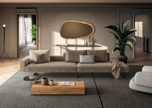 Fabric furniture maintenance in a modern luxury living room featuring a grey sectional sofa, plush armchair, and minimalist wooden coffee table with natural light streaming in.
