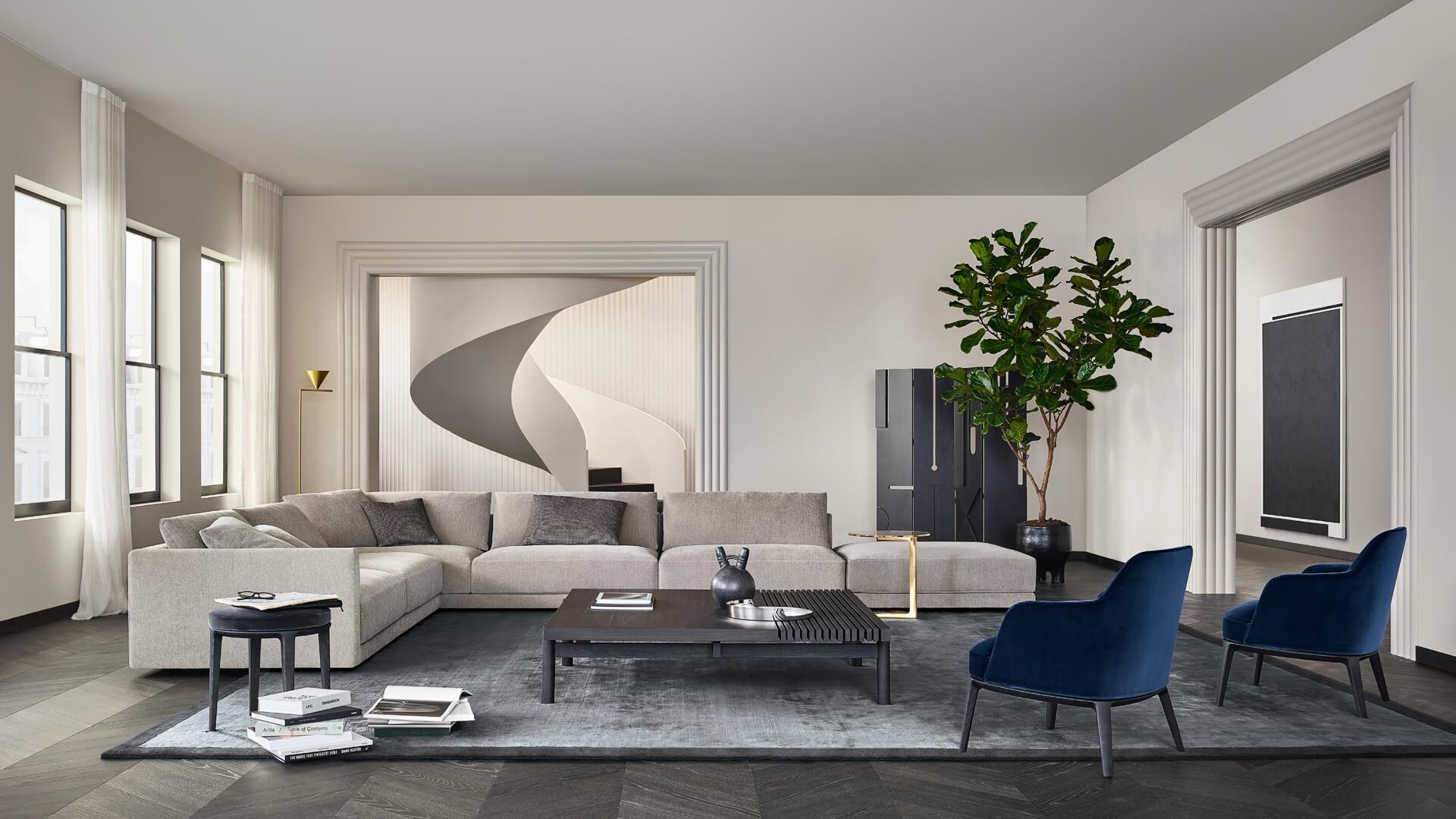 Modern living room with a large grey sectional sofa, navy accent chairs, and a textured rug in a minimal neutral-toned interior.