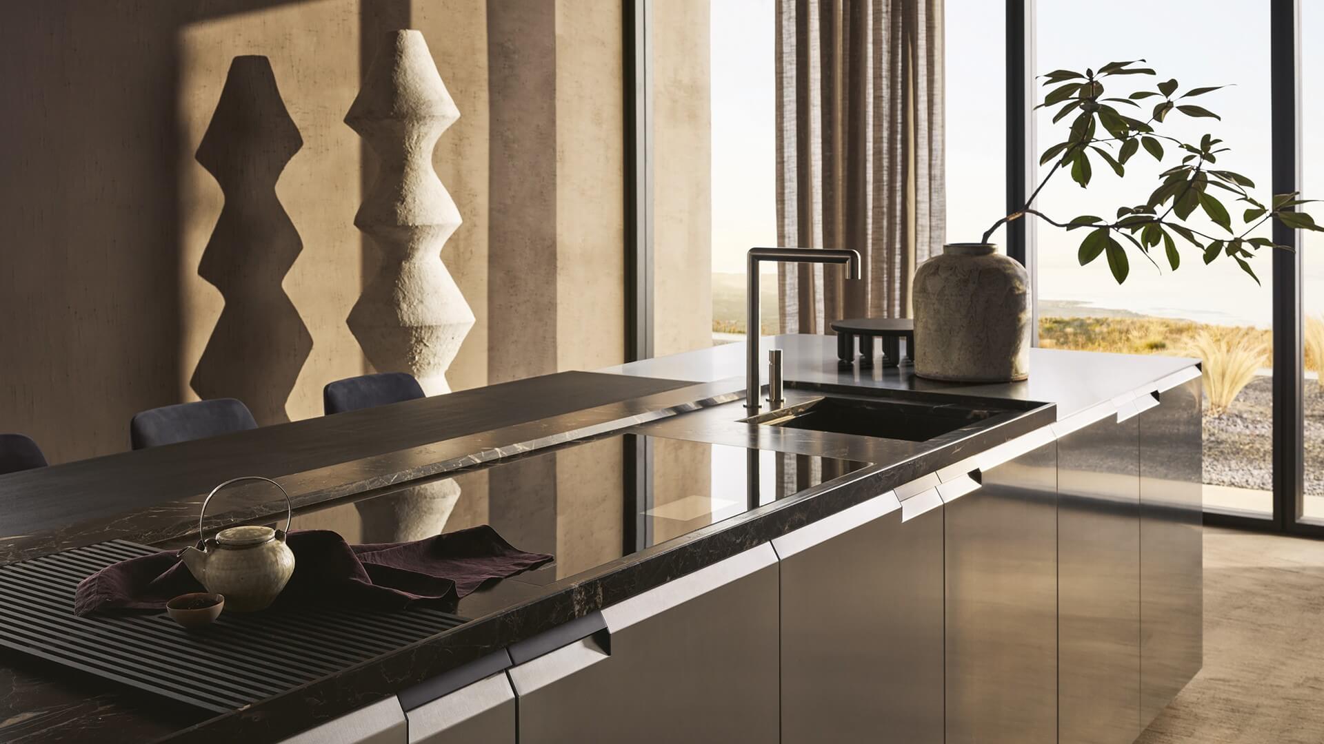 A luxurious kitchen with a dark countertop and minimalist modular kitchen furniture, showcasing the latest kitchen furniture trends.