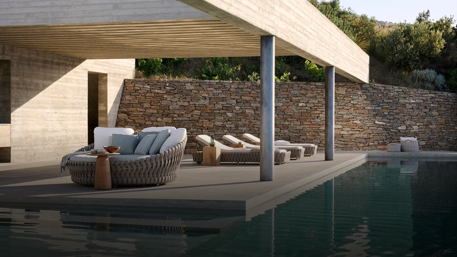 A luxurious poolside lounge area with a round daybed and chaise lounges, showcasing an outdoor furniture brand that uses next-generation synthetics for all-weather durability.