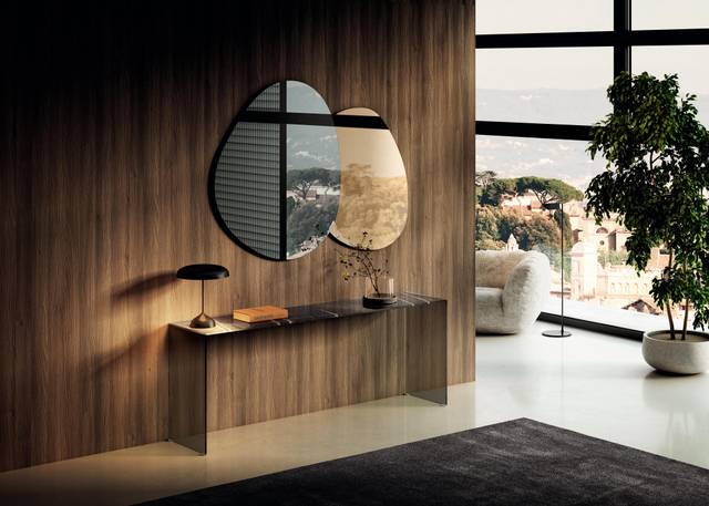 Modern console table setup with asymmetrical mirrors, a black lamp, and minimal decor against a wood-paneled wall in a high-rise living space.