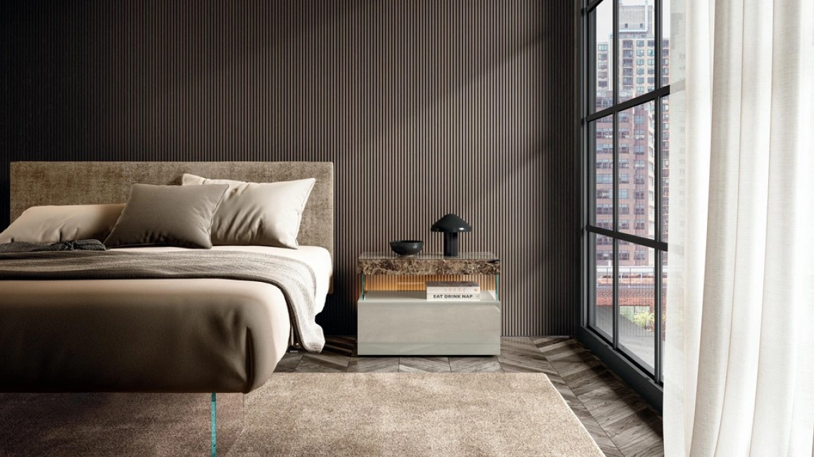 Modern bedroom with a minimalist nightstand beside an upholstered bed, styled with soft lighting and neutral tones