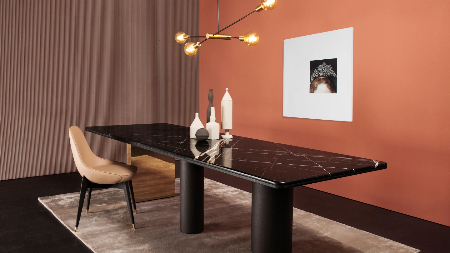 A luxury marble dining table design with a black stone top and white veining, paired with a modern tan leather chair