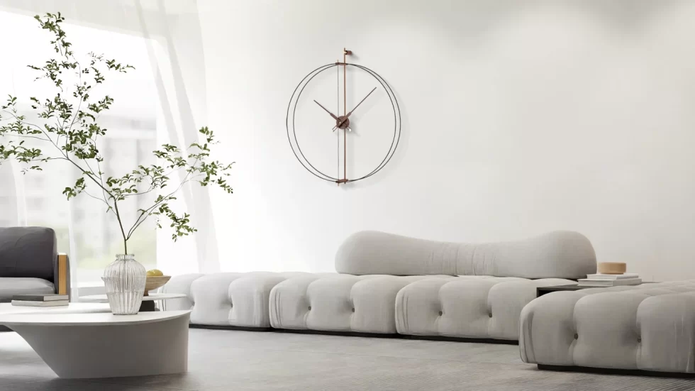 A large minimalist designer wall clock with a thin double-hoop frame hanging above a modern grey tufted sofa, creating elegant living room wall décor.