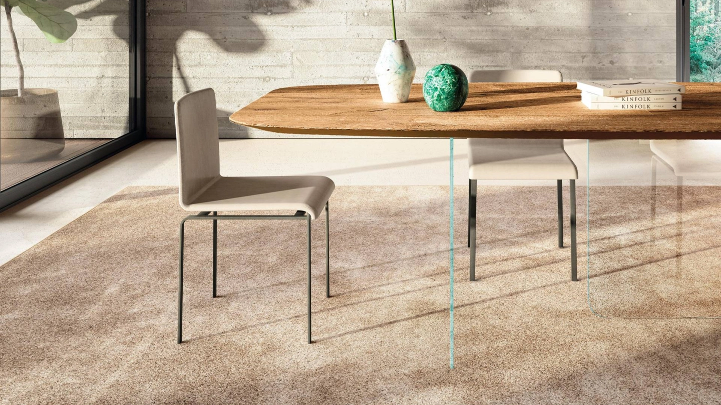 A contemporary Ventura Interiors dining room featuring a solid wood dining table with a natural grain, styled with minimalist chairs and a textured rug, demonstrating