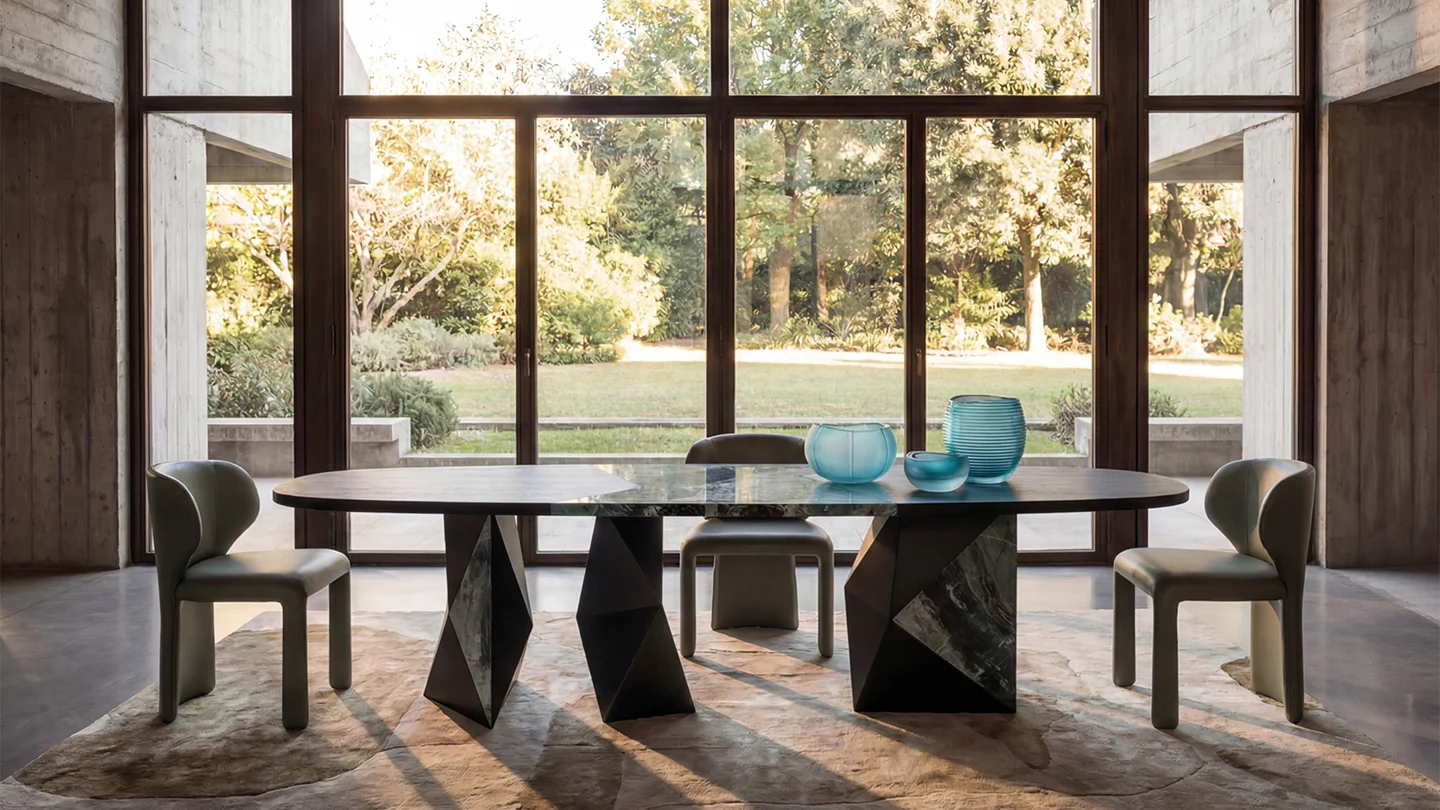 Modern dining room with a sculptural dining table, contemporary chairs and large windows overlooking a garden
